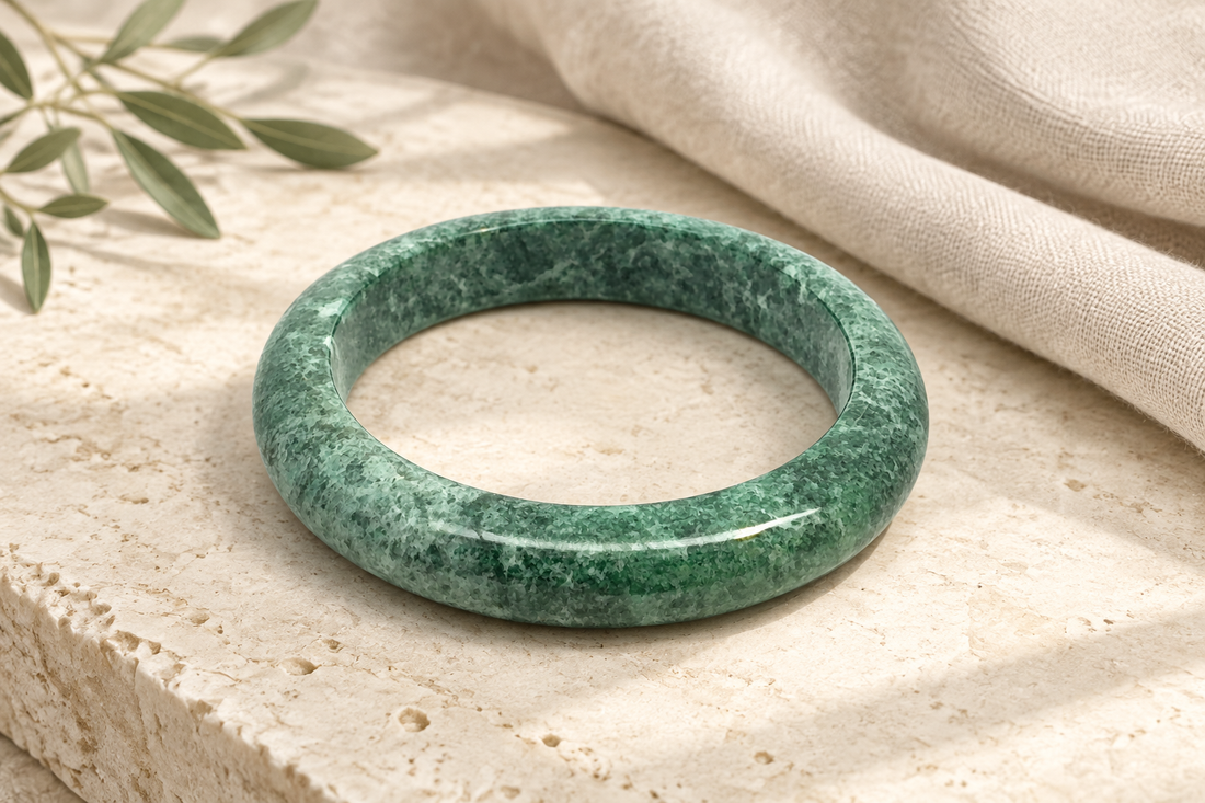 Illustrative rich mottled green Kazakh jadeite bangle inspired by an active ZHAUHAR catalogue item, styled on warm ivory limestone